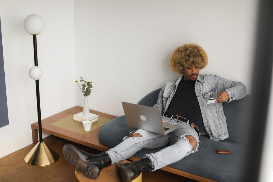 Man using credit card for online shopping on a couch at home.