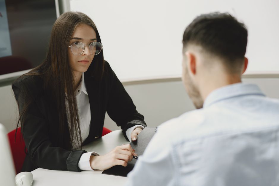 Two professionals engage in a serious business meeting at a modern office setting.