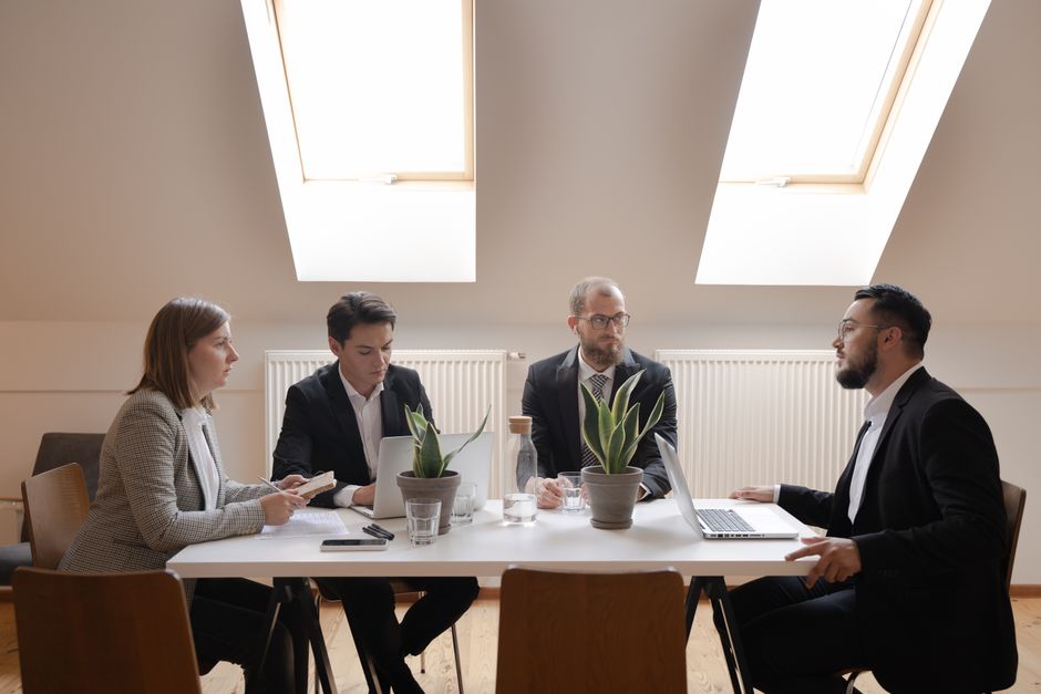 Diverse group of professionals in formal meeting around a table.