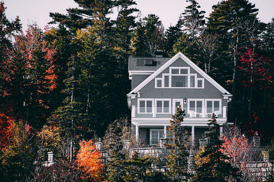 Elegant family home set against a vibrant autumn forest backdrop.