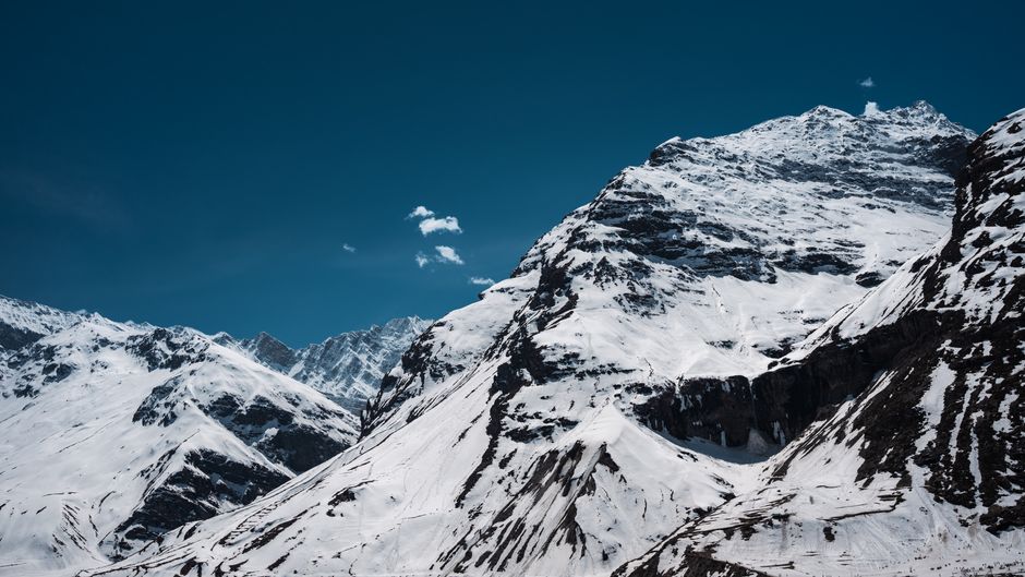 Majestic snow-covered mountains under a clear blue sky in Sissu, Himachal Pradesh, India.